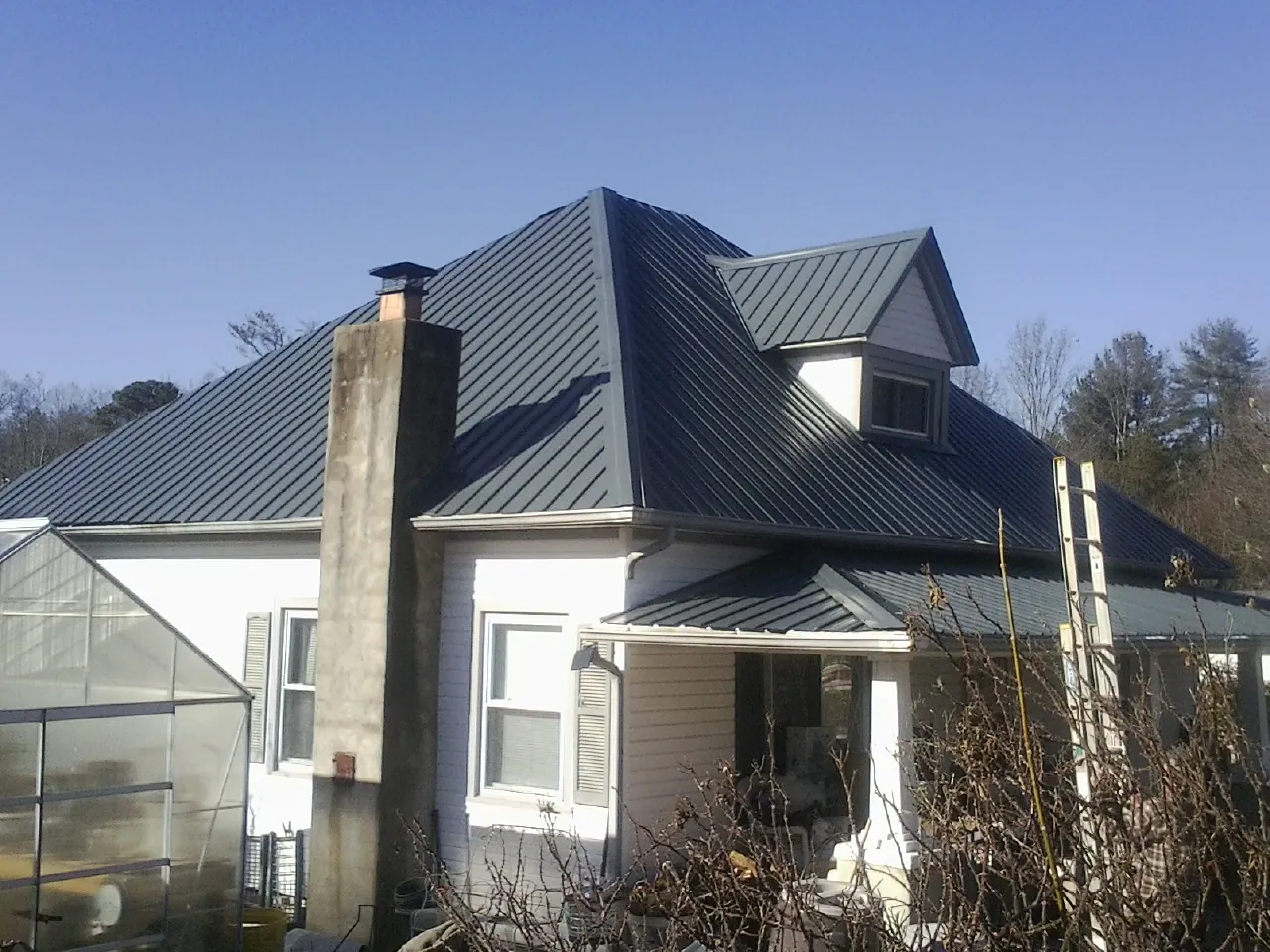 Dark blue standing seam metal roof on a white farmhouse with dormer — Slate & Tile Roof Repair by Roofing Brothers in Weimar