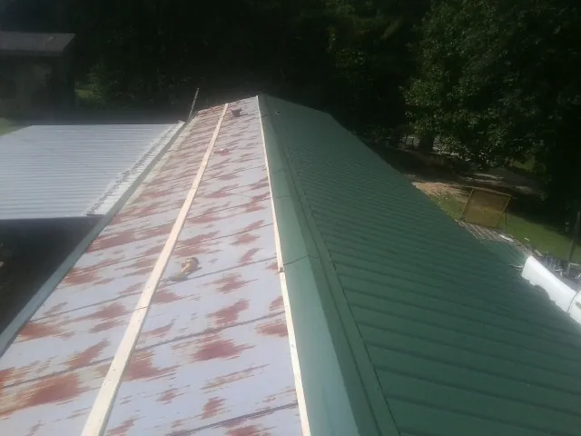 Old rusted panels beside newly installed green metal roofing — Wind Damage Roof Repair by Roofing Brothers in Weimar