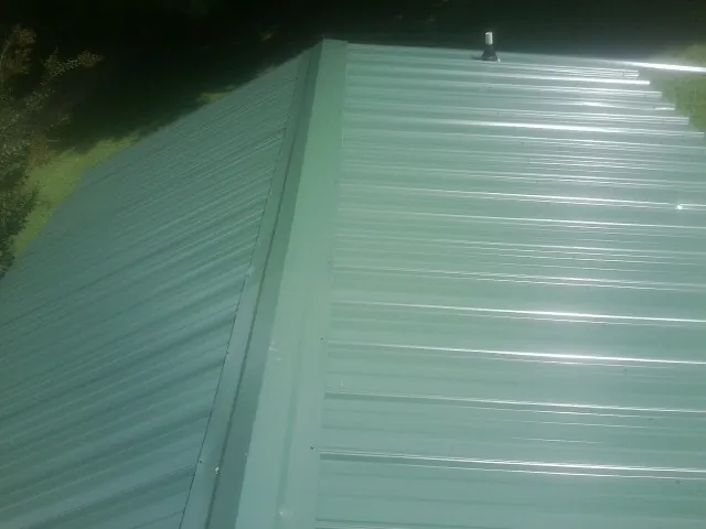 New green metal panels meeting at the ridge of a roof — Flat Roof Repair work by our crew in Weimar