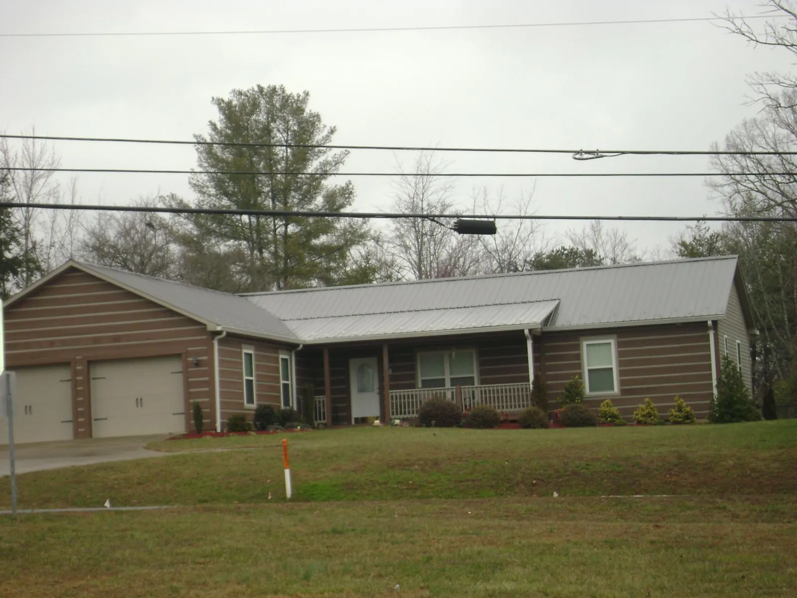Gray metal roof on a log sided ranch home with a front porch in Weimar