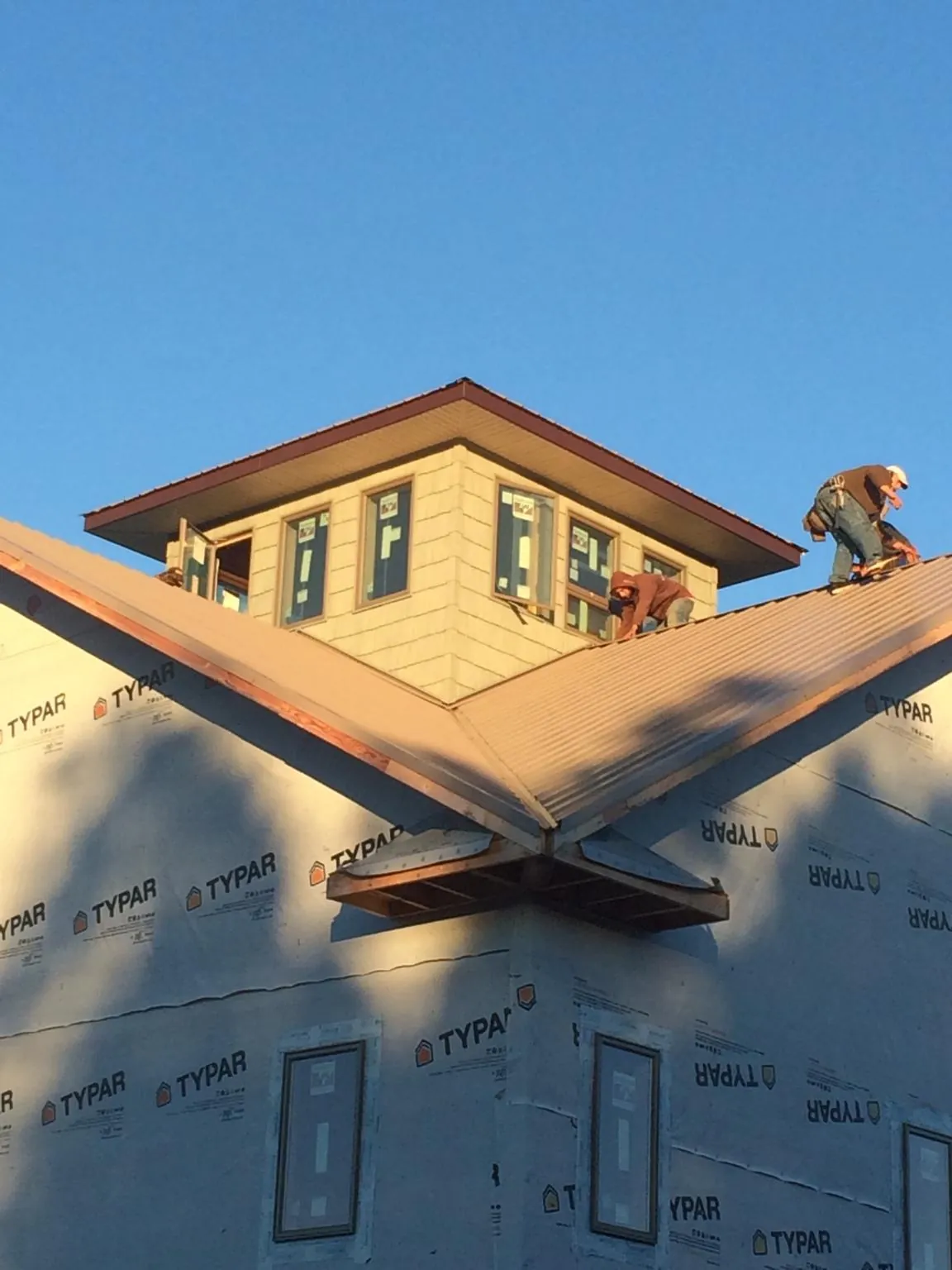 Roofers working around a rooftop cupola on a new metal roof at sunset — Roof Waterproofing in Weimar by Roofing Brothers